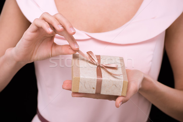 Close-up partial view of woman in pink dress holding gift box on black, international womens day con Stock photo © LightFieldStudios