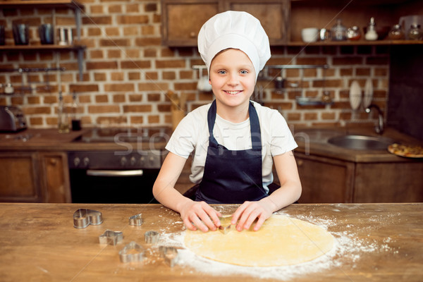 portrait of little boy in chef hat making shaped cookies in kitchen Stock photo © LightFieldStudios