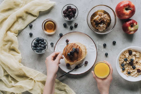 partial top view of person eating healthy breakfast with homemade pancakes, fresh fruits and honey o Stock photo © LightFieldStudios