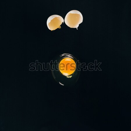 close up view of raw egg yolk falling on frying pan isolated on black Stock photo © LightFieldStudios