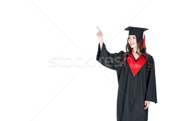 Beautiful young brunette woman in academic gown pointing away with finger Stock photo © LightFieldStudios