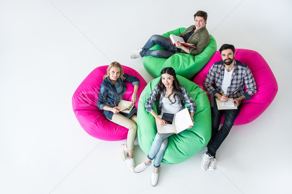 overhead view of students sitting on beanbag chairs and studying in studio on white  Stock photo © LightFieldStudios