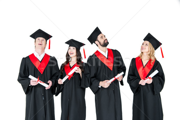 Group of young men and women in graduation gowns and mortarboards holding diplomas Stock photo © LightFieldStudios