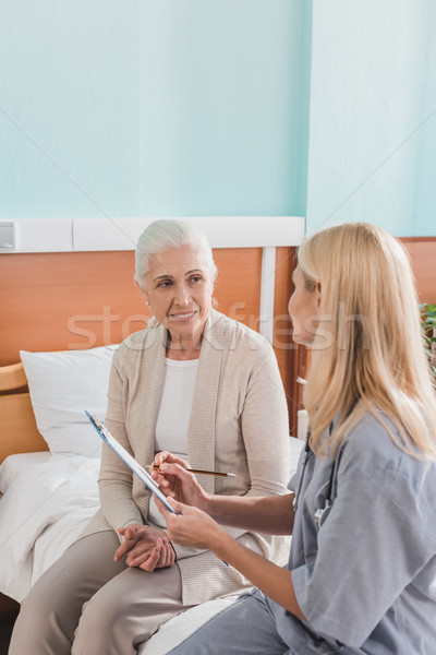 Starszy kobieta pielęgniarki schowek uśmiechnięty patrząc Zdjęcia stock © LightFieldStudios