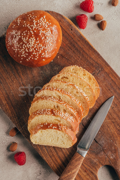flat lay with freshly baked cut pastry on wooden cutting board, knife and raspberries on light surfa Stock photo © LightFieldStudios