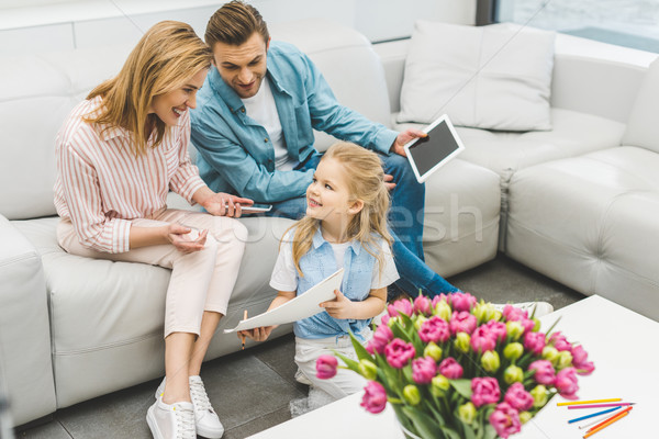 smiling daughter showing parents with digital devices picture at home Stock photo © LightFieldStudios
