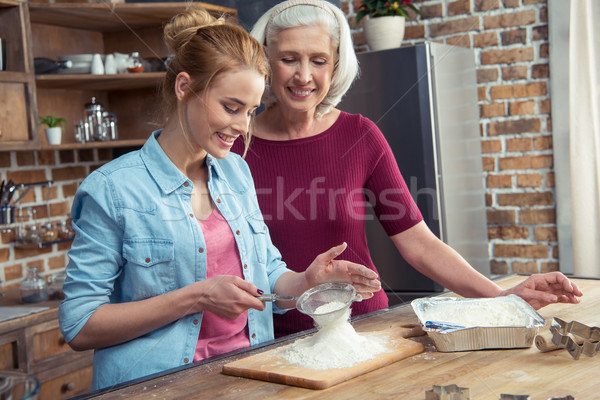 Grandmother and granddaughter sifting flour Stock photo © LightFieldStudios