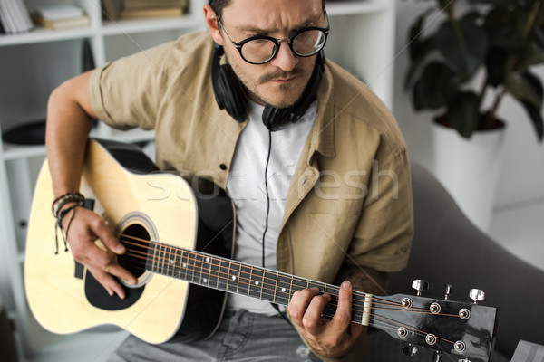 Człowiek gry gitara koncentruje elegancki słuchawki Zdjęcia stock © LightFieldStudios