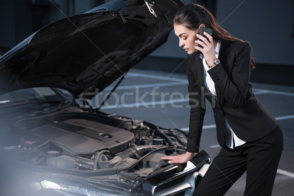 Stock photo: woman looking under hood of car