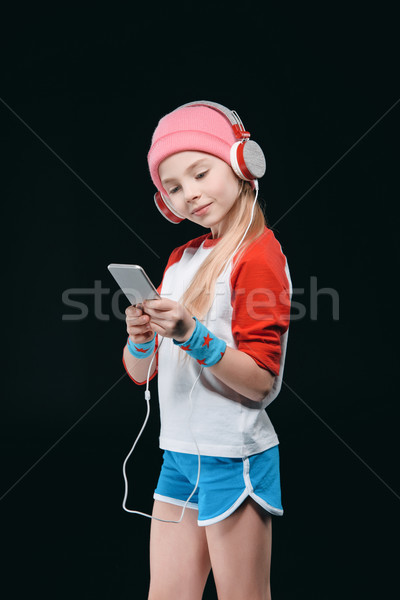 Cute sporty girl in headphones using smartphone isolated on black, activities for children concept   Stock photo © LightFieldStudios