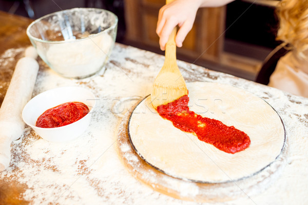 partial view of girl putting tomato sauce on pizza dough Stock photo © LightFieldStudios