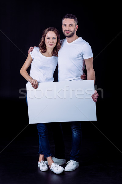 Smiling couple holding blank card Stock photo © LightFieldStudios