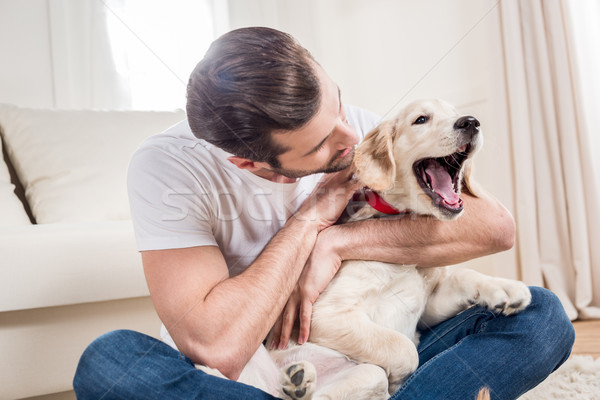 [A stock photo of a man cuddling an excited puppy in his lap]