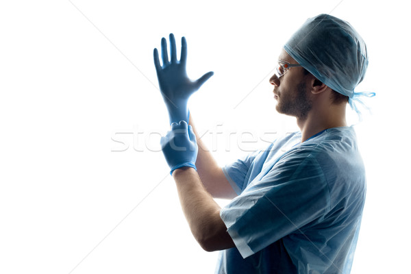 side view of surgeon in medical uniform wearing gloves on white Stock photo © LightFieldStudios