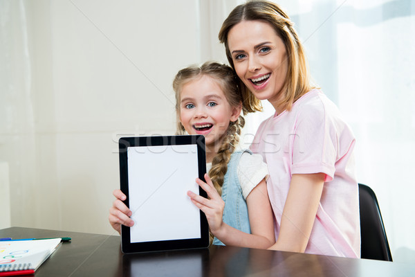 Happy mother and daughter showing digital tablet at home Stock photo © LightFieldStudios