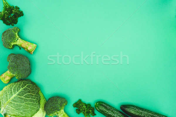 top view of fresh raw broccoli, parsley, cucumbers and savoy cabbage isolated on green background Stock photo © LightFieldStudios
