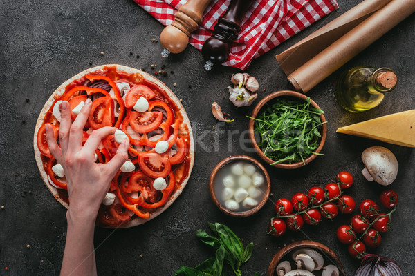 cropped shot of woman spreading mozzarella pieces onto pizza on concrete table Stock photo © LightFieldStudios