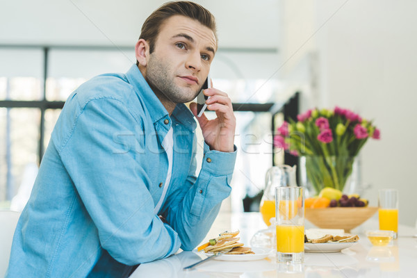 portrait of man talking on smartphone during breakfast at home Stock photo © LightFieldStudios