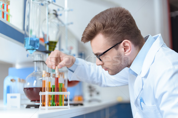 Side view of young man scientist holding test tube with reagent in lab Stock photo © LightFieldStudios