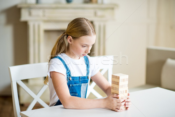 Concentrated preteen girl building tower from wooden bricks on table Stock photo © LightFieldStudios