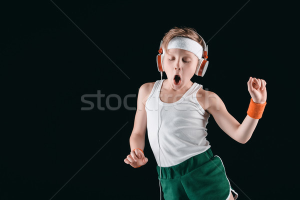 portrait of sportive boy listening music in headphones isolated on black Stock photo © LightFieldStudios