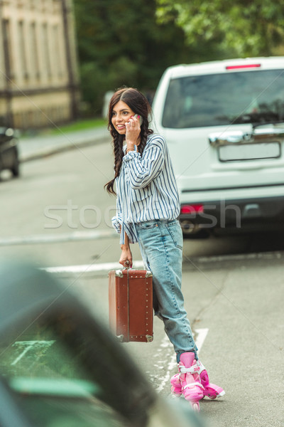 Stock photo: girl in roller skates with smartphone and suitcase