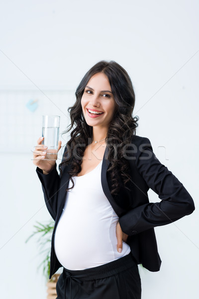 Embarazadas mujer de negocios vidrio agua feliz mirando Foto stock © LightFieldStudios