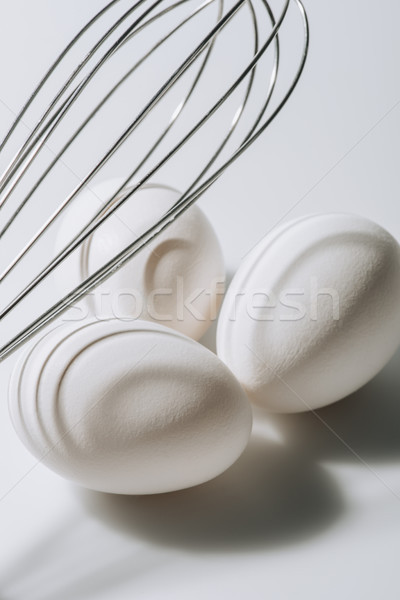 white eggs laying under whisk on white background Stock photo © LightFieldStudios