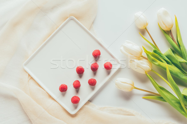 top view of fresh ripe raspberries and beautiful tulip flowers Stock photo © LightFieldStudios