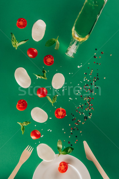 close up view of mozzarella cheese, cherry tomatoes, spinach, spices and olive oil falling on plate  Stock photo © LightFieldStudios