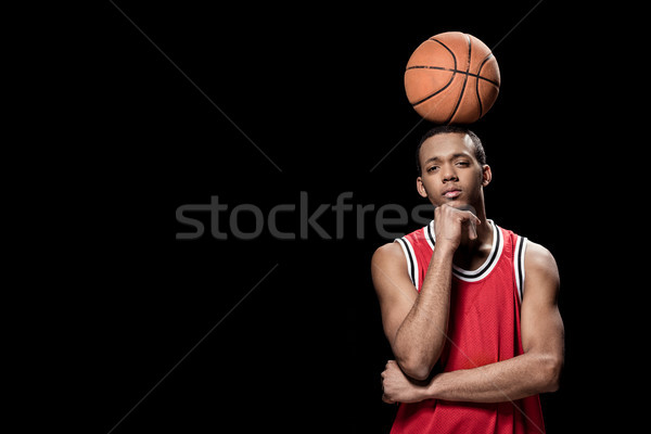 Young confident basketball player posing with ball on head on black  Stock photo © LightFieldStudios