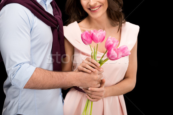 Stock photo: partial view of man presenting tulips bouquet to smiling woman on black, international womens day co