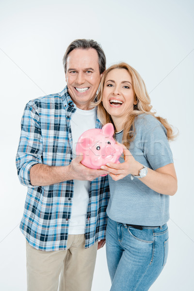 Front view of happy couple holding piggy bank on white Stock photo © LightFieldStudios