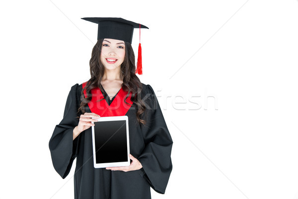 Beautiful young brunette woman in mortarboard holding digital tablet and smiling Stock photo © LightFieldStudios