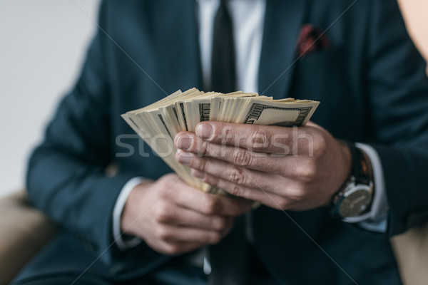 Stock photo: partial view of stylish businessman holding dollar banknotes on grey