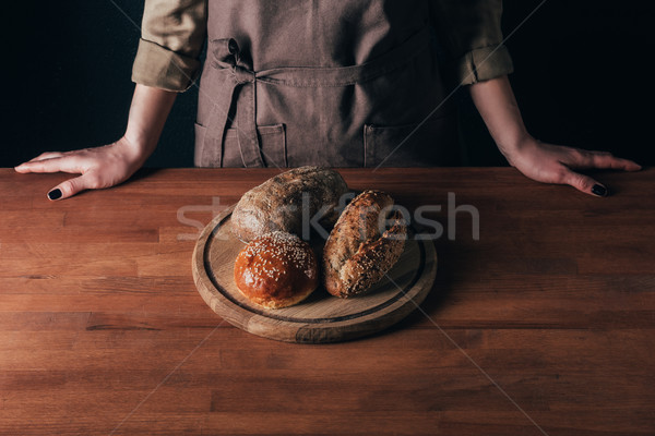 partial view of woman standing at table with loafs of bread on wooden cutting board Stock photo © LightFieldStudios