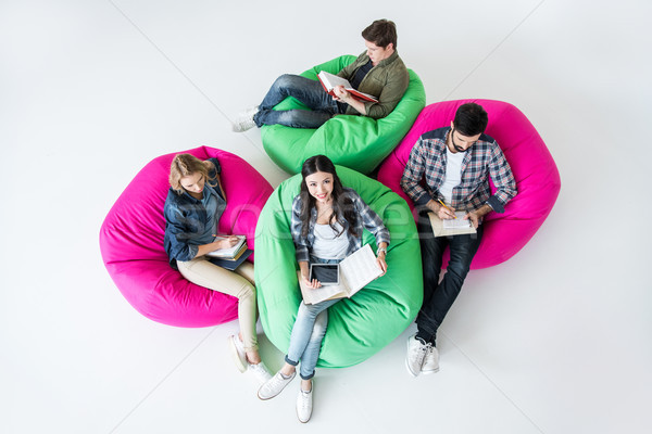 overhead view of students sitting on beanbag chairs and studying in studio on white  Stock photo © LightFieldStudios