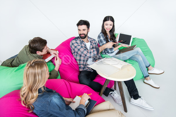 students sitting on beanbag chairs and studying with digital tablet in studio on white  Stock photo © LightFieldStudios