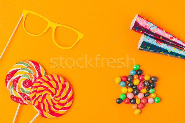 flat lay with sweets, lollipops and party objects isolated on orange, purim holiday concept Stock photo © LightFieldStudios