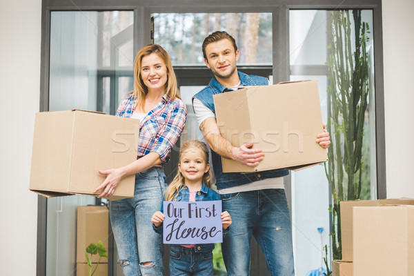 portrait of smiling parents and daughter with our new house board in hands, moving home concept Stock photo © LightFieldStudios