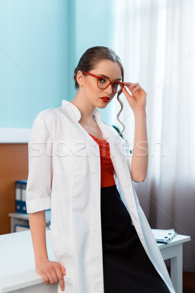portrait of confident professional doctor in white coat and glasses in cabinet Stock photo © LightFieldStudios