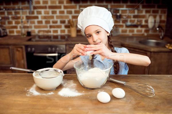 Stock photo: little girl in chef hat making dough for cookies