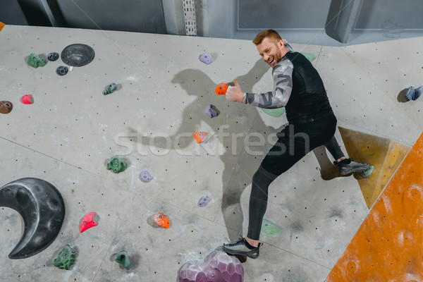 Man on climbing wall showing thumb-up Stock photo © LightFieldStudios