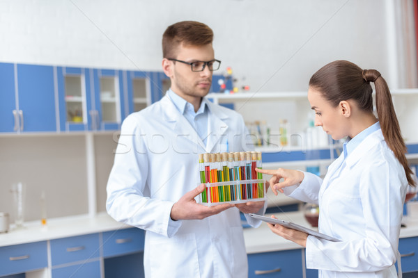 Professional chemists in white coats inspecting test tubes with reagents in lab Stock photo © LightFieldStudios