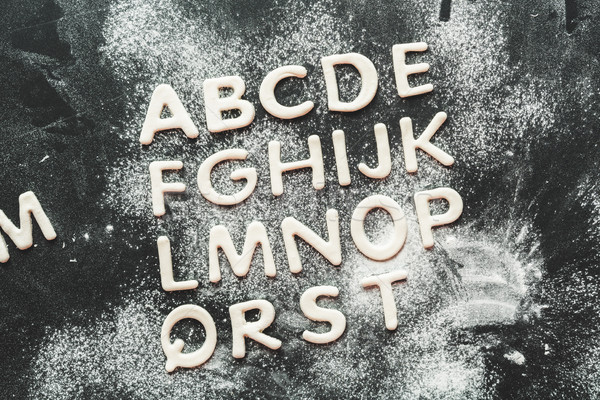 top view of dough for cookies in forms of letters with flour, cookie dough Stock photo © LightFieldStudios