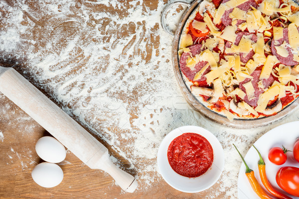 top view of pizza ingredients, tomatoes, salami and mushrooms on wooden tabletop Stock photo © LightFieldStudios