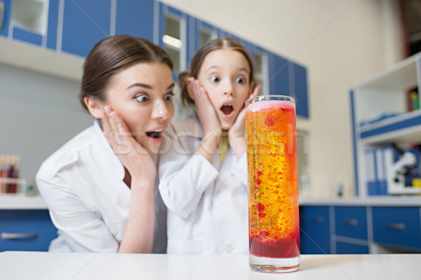 shocked woman teacher and girl student scientists looking at experimental tube in lab Stock photo © LightFieldStudios