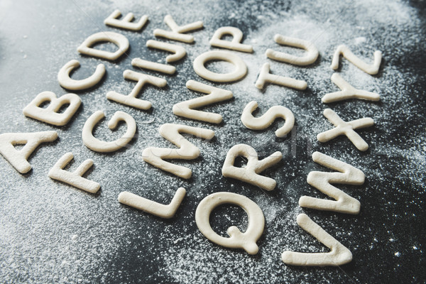 close up of dough for cookies in forms of letters with powdered sugar, cookie dough Stock photo © LightFieldStudios