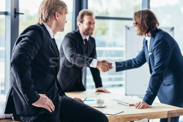 Empresarios apretón de manos empresario mirando colegas oficina Foto stock © LightFieldStudios