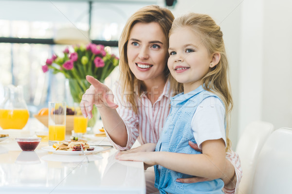 Glimlachende vrouw tonen iets dochter ontbijt home Stockfoto © LightFieldStudios